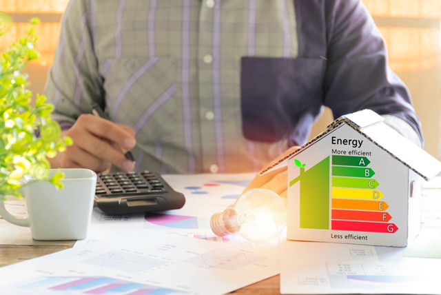 Men who are calculating cost savings from energy. Hand holding a pen. Detail of house efficiency rating on digital tablet screen. Concept of ecological and bio energetic house. Energy class.